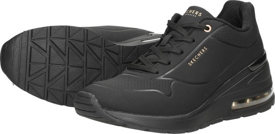 Een paar zwarte Skechers sneakers, met zolen zichtbaar, gouden details.