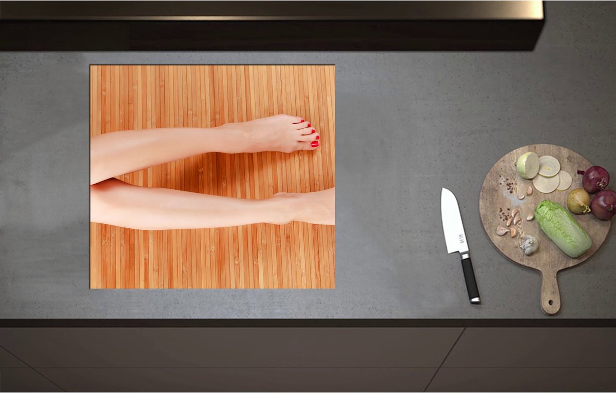 Inductieplaat Beschermer - Bovenaanzicht van Vrouwen Benen met Roodkleurige Teennagels op Houten Ondergrond - 60x55 cm - 2 mm Dik - Inductie Beschermer - Bescherming Inductiekookplaat - Kookplaat Beschermer van Zwart Vinyl