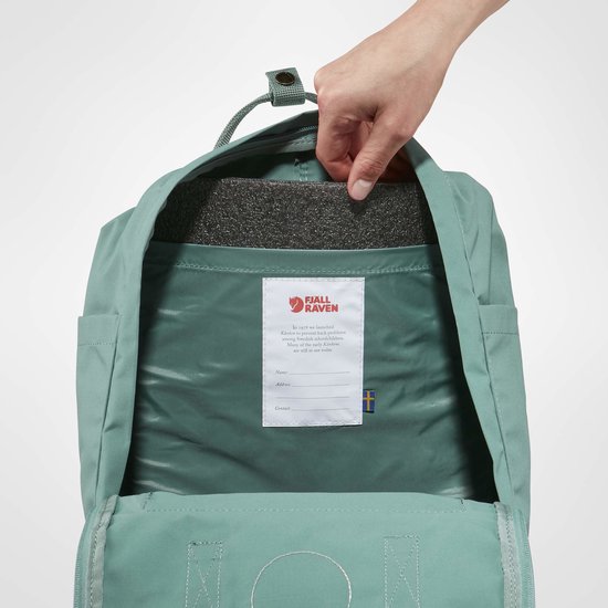 Binnenzijde van een groene Kånken rugzak met schuimrubber en een naamlabel.