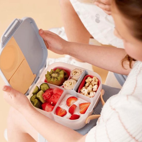Boîte à lunch b.box bleu clair ouverte, remplie de fruits, concombre, rouleaux et popcorn.