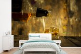 Behang - Fotobehang Barman schenkt glas whisky in - Breedte 390 cm x hoogte 260 cm
