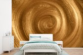 Behang - Fotobehang Een vortex in goudkleurige verf - Breedte 600 cm x hoogte 400 cm