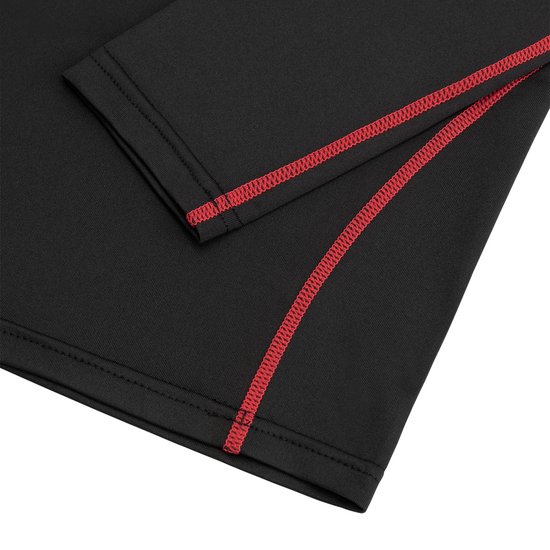 Détail de l'ourlet d'un t-shirt de sport noir à manches longues avec coutures rouges.