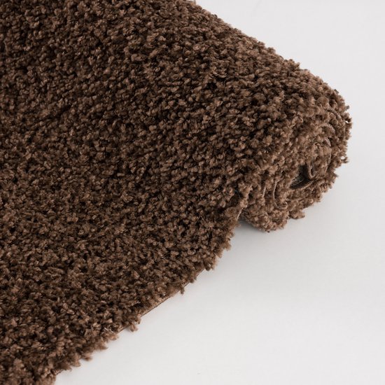 Bruin shaggy vloerkleed met een pluizige, hoogpolige textuur. Het kleed is opgerold en ligt op een witte achtergrond.