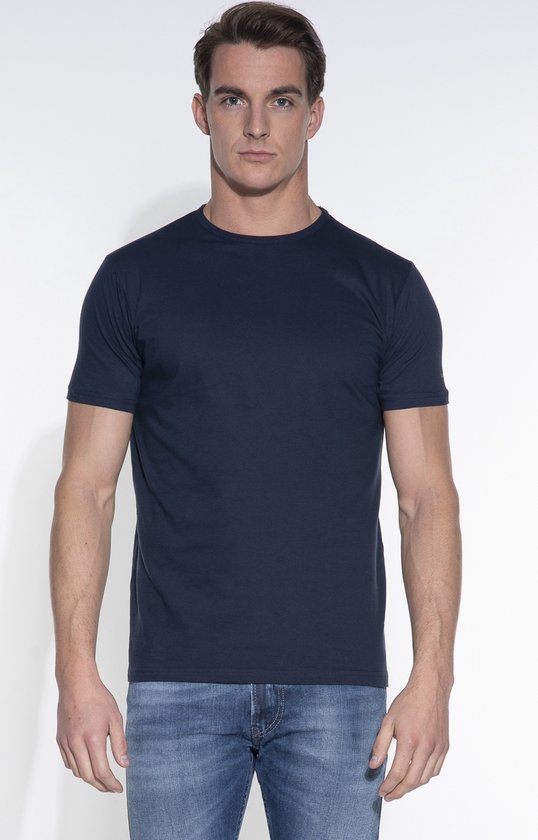 Man met donkerblauw T-shirt met ronde hals, korte mouwen en jeans.