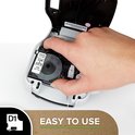Hand plaatst een zwarte/witte Dymo D1 tape cassette in een labelmaker.