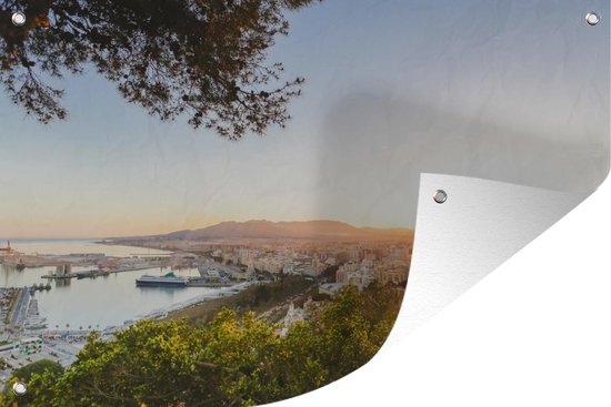 Tuinposter Uitzicht op de haven van Málaga tussen de Spaanse bomen - 130x80 cm - Wanddecoratie Buiten - Tuinposter - Tuindoek - Schuttingposter - Tuinschilderij