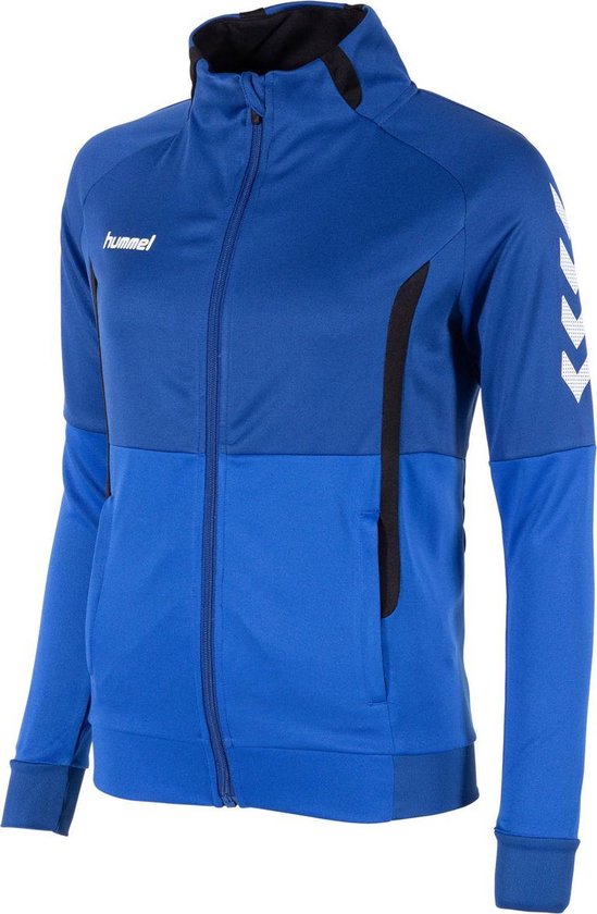 Model draagt blauw Hummel sportvest met rits, zwarte details en witte chevrons op de mouwen.