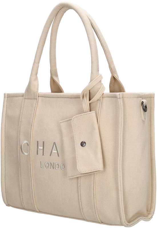 Beige canvas handtas van Charm London met "CHA LONDON" logo, zijwaarts bekeken.