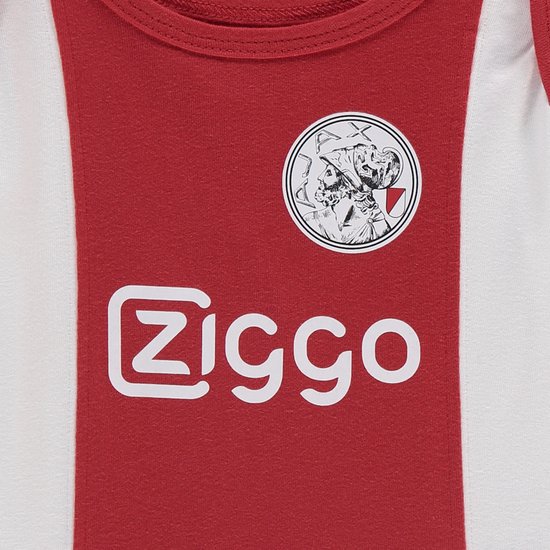 Close-up van de voorkant van een Ajax baby romper. Wit 'Ziggo' logo en het Ajax-embleem op rode band.
