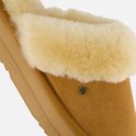 Detailopname van cognacbruine suède pantoffel met crèmekleurige bontvoering.