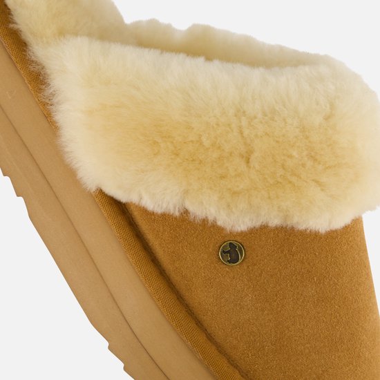Detailopname van cognacbruine suède pantoffel met crèmekleurige bontvoering.