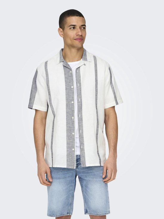 Man in wit kort overhemd met verticale grijze strepen en jeansshort.