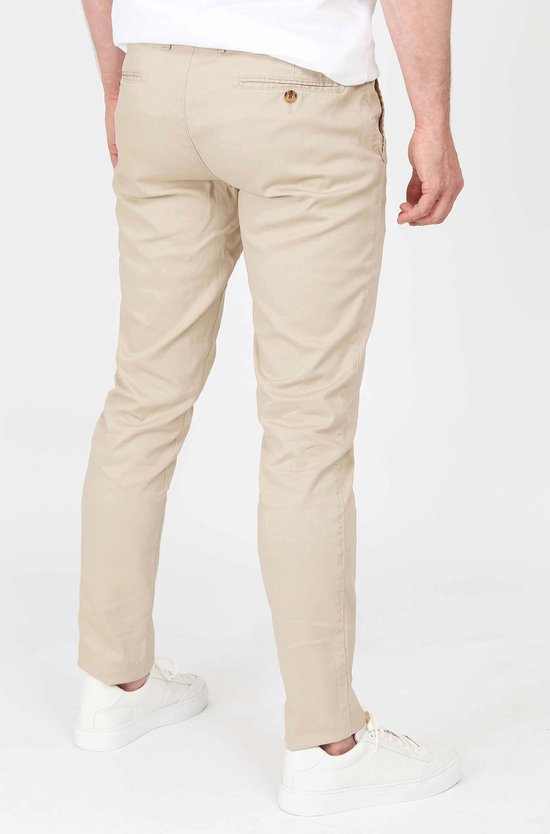 Achterkant van een mannen chino in lichtbeige, gedragen met witte sneakers.