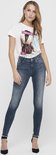 Model met blauwe skinny jeans met raw-edge enkelbroekspijpen en een t-shirt met print.