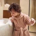 Peignoir rose à capuche, porté par un enfant près d'une baignoire.