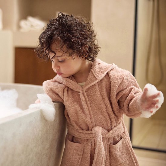 Peignoir rose à capuche, porté par un enfant près d'une baignoire.