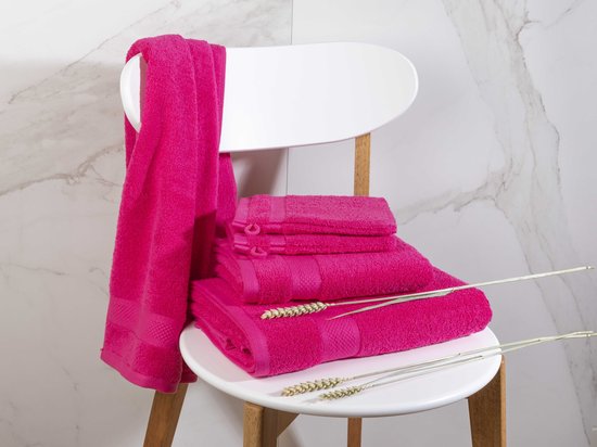 Roze handdoeken op een witte stoel met een marmeren achtergrond en tarwearen.