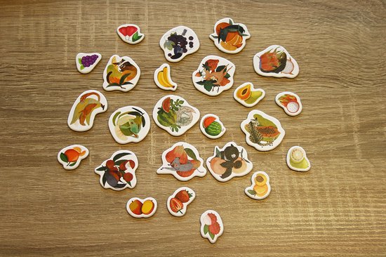 Veelkleurige fruitvormige speelstukken verspreid over een houten tafel.