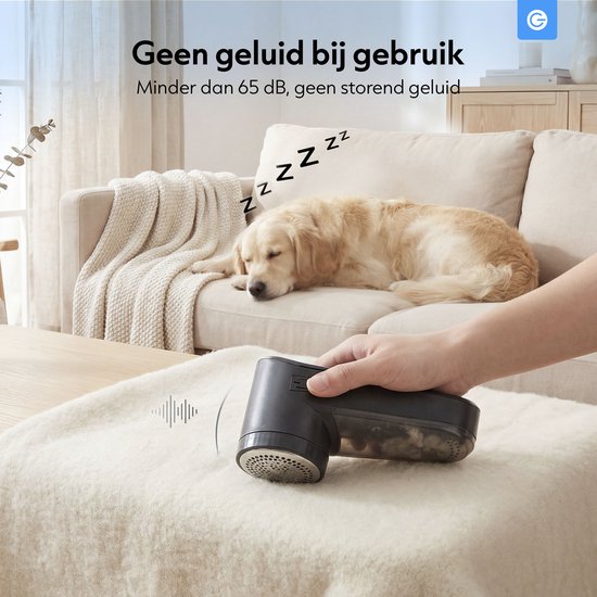 Hand gebruikt zwarte pluizenverwijderaar op lichte bank, hond slaapt op de achtergrond.