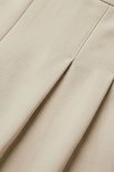 Detail van beige stof met een verticale naad en plooi.