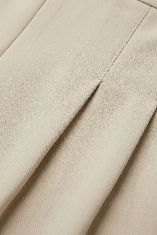 Detail van beige stof met een verticale naad en plooi.