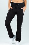 Zwarte trainingsbroek met witte ritsen, zwart koord en wit accent op de witte sneakers.