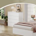 Commode blanche à 8 tiroirs dans une chambre, à côté d'un lit.