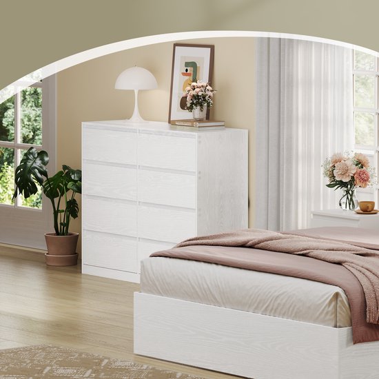 Commode blanche à 8 tiroirs dans une chambre, à côté d'un lit.
