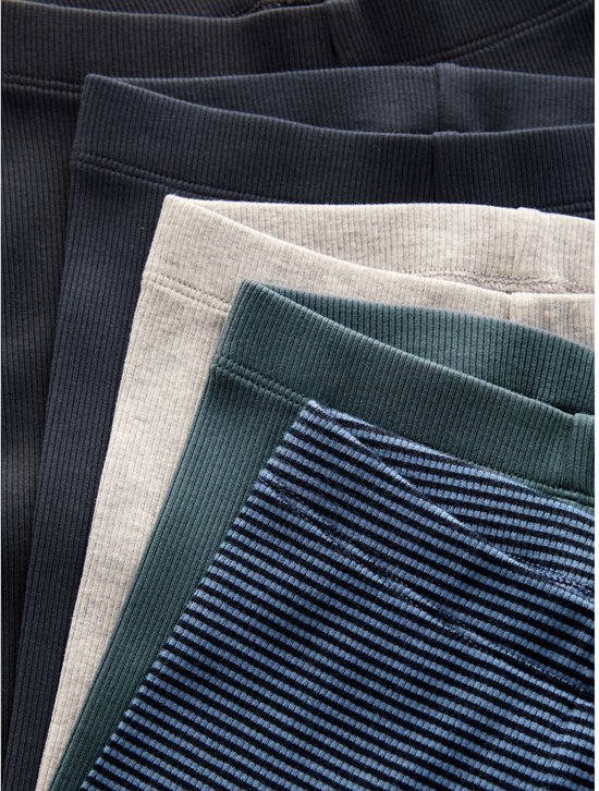 Detail van vijf geribbelde leggings in donkerblauw, groen, grijs, zwart en blauw gestreept.