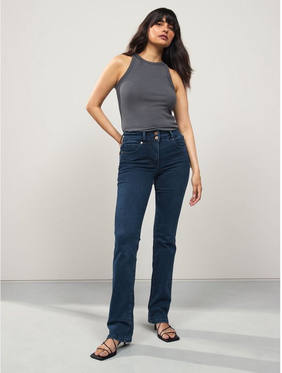 Model draagt een donkerblauwe spijkerbroek met bootcut pasvorm en slim-fit model. De broek heeft een hoge taille met dubbele knoopsluiting.