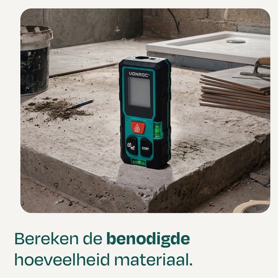 Zwarte en groene VONROC laser afstandsmeter op een betonnen ondergrond in een bouwomgeving.