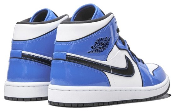 Achterkant van een paar blauw-witte Air Jordan 1 Mid SE sneakers met zwarte accenten en het Air Jordan logo.