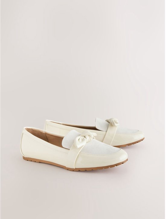 Off-white lakleren loafers met strik, op witte achtergrond.