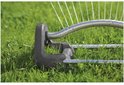 Zwenksproeier met grijze basis op gras, waterstralen spuiten.