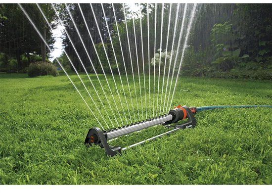 Zwenksproeier met oranje en zwarte accenten, sproeiend op groen gras.