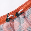 Close-up van de tailleband van een oranje zwembroek met groene dino print, mesh voering en trekkoord.
