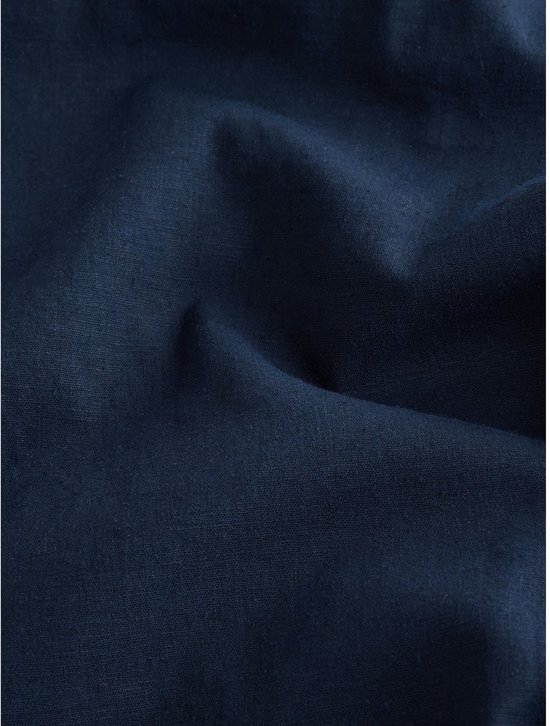 Close-up van de textuur van donkerblauwe linnenmix stof met natuurlijke plooien.