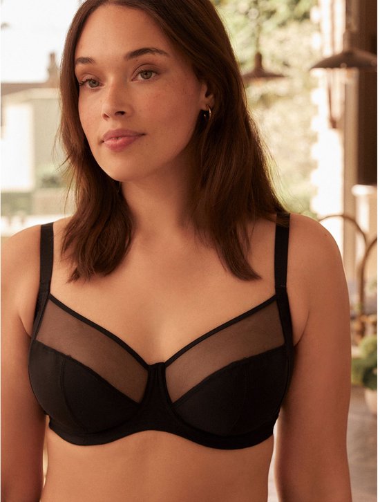 Model draagt zwarte beha met gaasdetails en heeft het haar los.