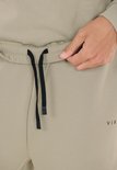 Sluiting van beige trainingsbroek met zwart trekkoord.