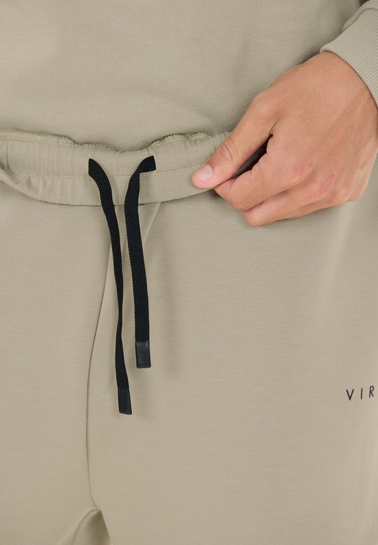 Sluiting van beige trainingsbroek met zwart trekkoord.