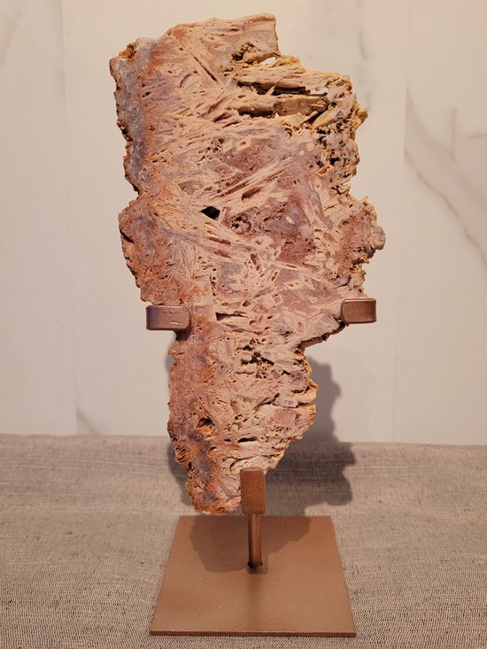 Een roze amethist slab met een gestructureerd oppervlak en natuurlijke holtes, staand op een metalen display.