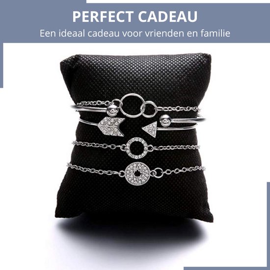Set van 5 zilverkleurige armbanden op zwart kussen: geknoopte bangle, pijlenbangle, en 3 schakelarmbanden met cirkels en ster.