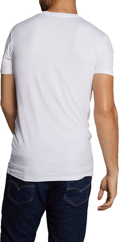 Achterkant van een man met baard die een wit T-shirt en een spijkerbroek draagt.