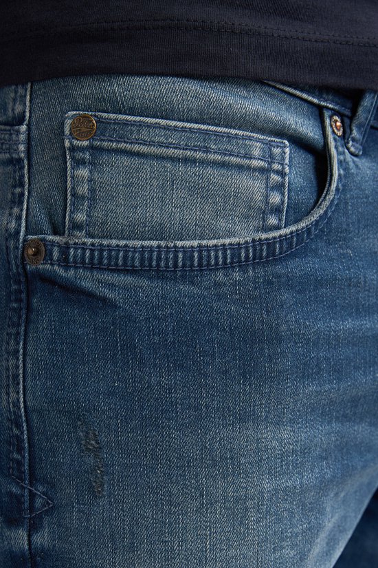 Gedetailleerde close-up van de denim jeans met een klein zakje en klinknagels. Vaal blauwe wassing met lichte beschadigingen.