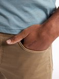 Close-up van de hand van een man in de zak van een bruine chino.