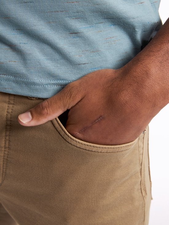 Close-up van de hand van een man in de zak van een bruine chino.