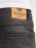 Detail van de achterkant van een zwarte jeans met een leren Petrol Industries label.