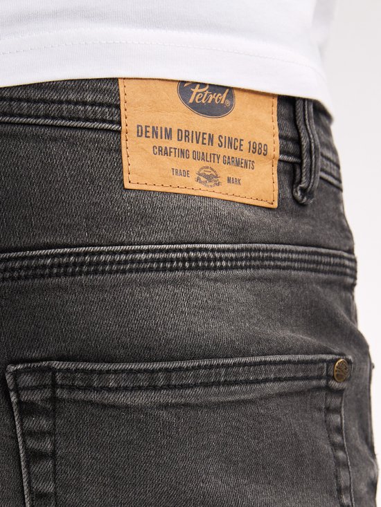 Detail van de achterkant van een zwarte jeans met een leren Petrol Industries label.