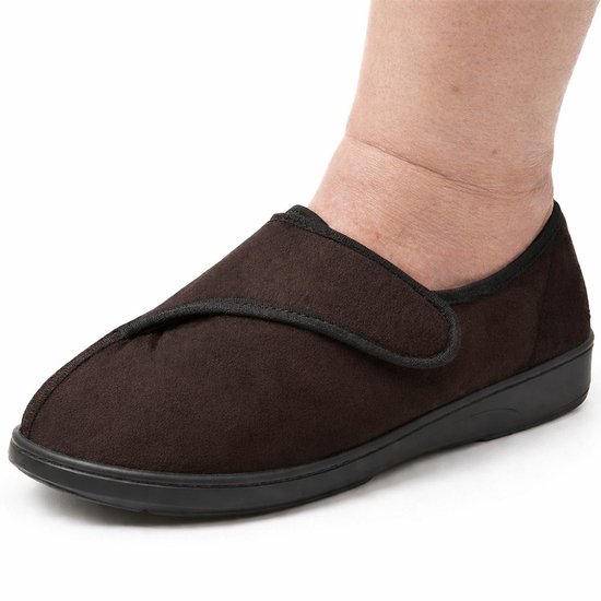 Bruine pantoffel met klittenbandsluiting, gedragen door een persoon met gezwollen enkel.
